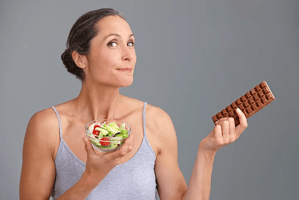 Frau zwischen Salat und Schokolade