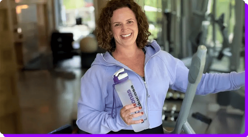 Andrea steht in Fitnessstudio mit Shake in der Hand